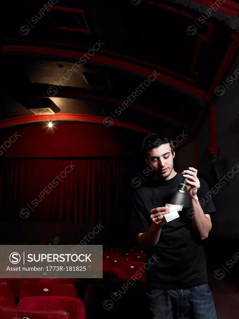 Cinema usher checking ticket with flashlight