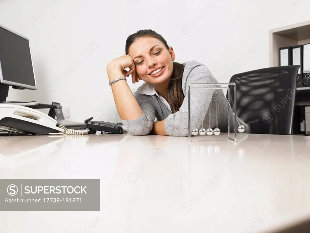 Businesswomen sitting at her desk with a Newton´s Cradle