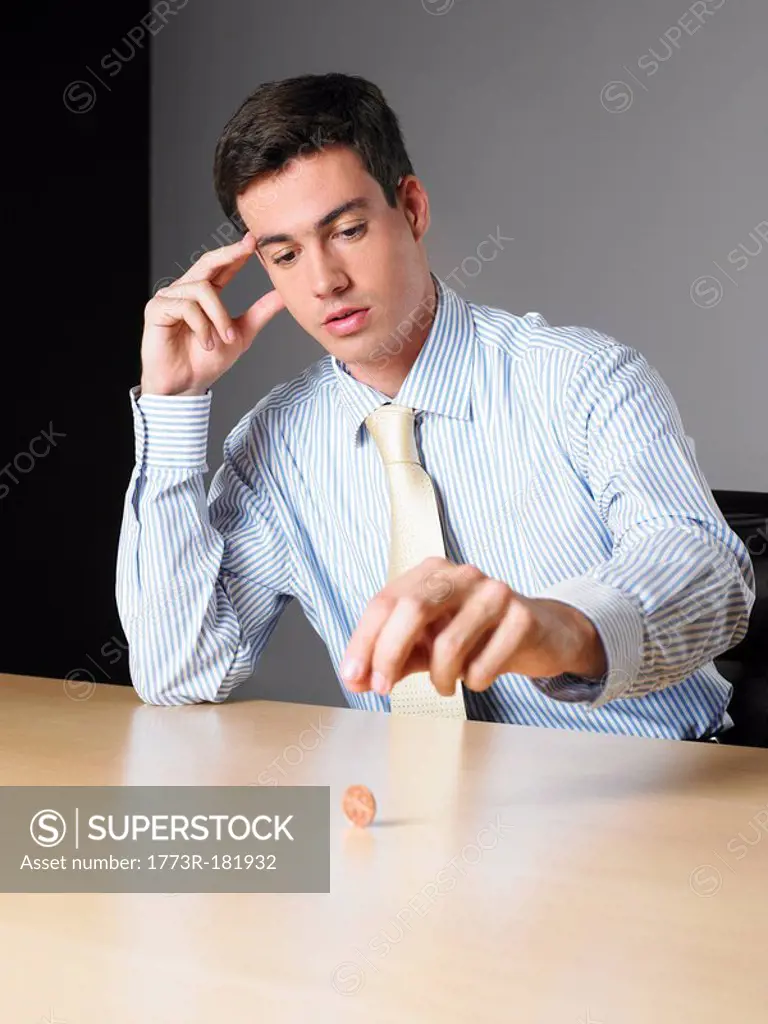 Businessman in an office spinning a penny on a desk