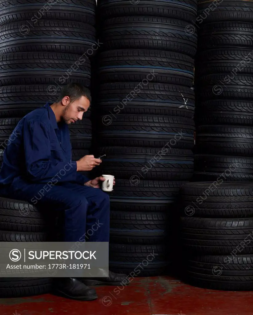Mechanic sitting on a stack of tires