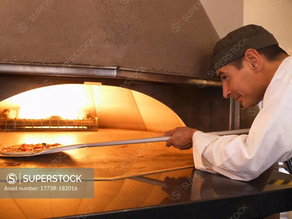 Pizza chef placing pizza in oven