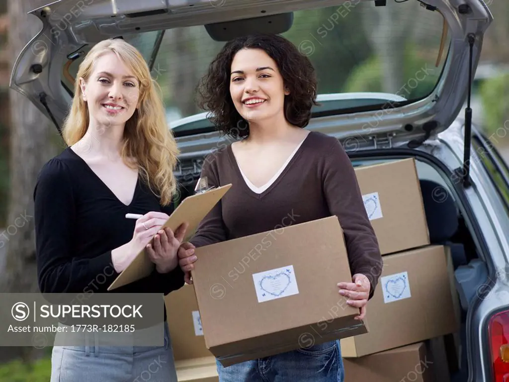 Two women checking boxes at car