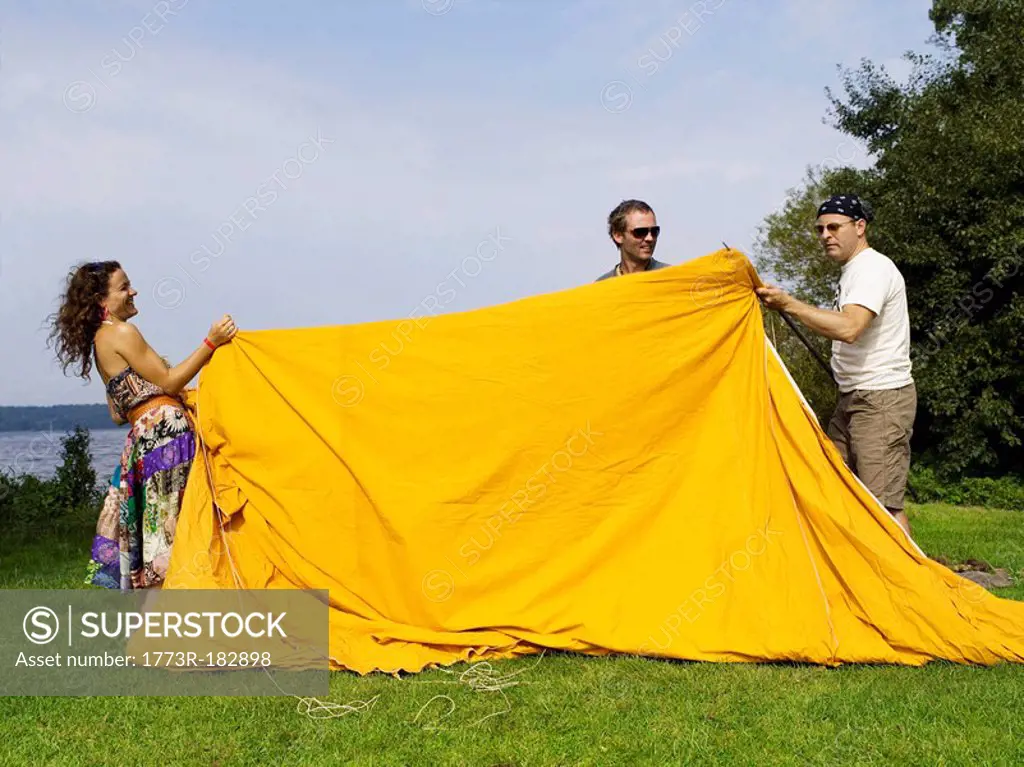 Three people setting up a tent