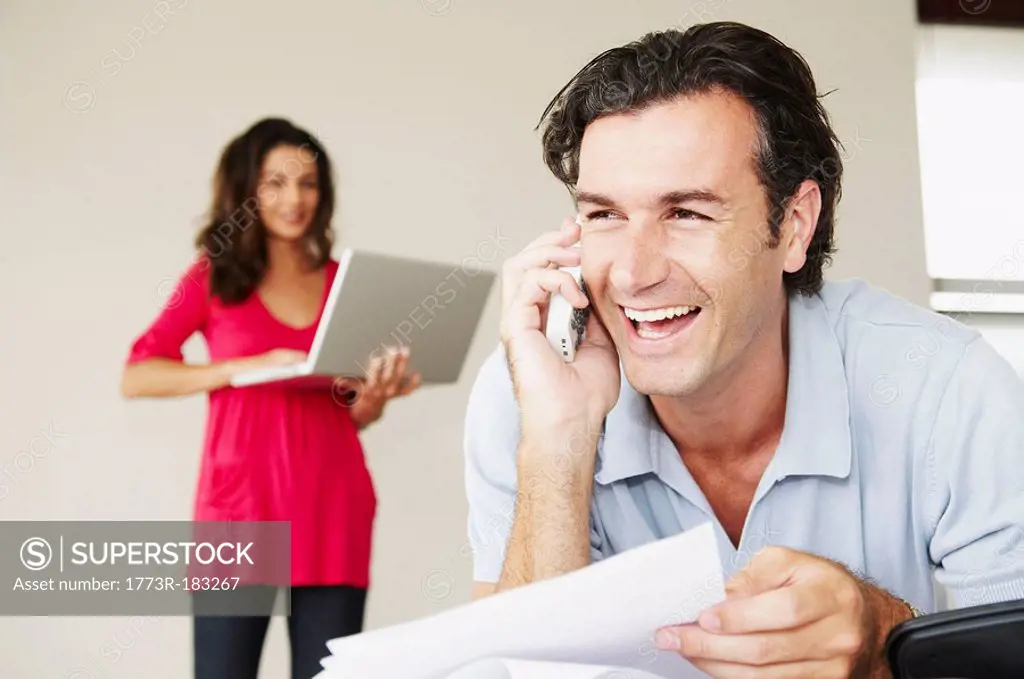 Smiling male on phone with bills