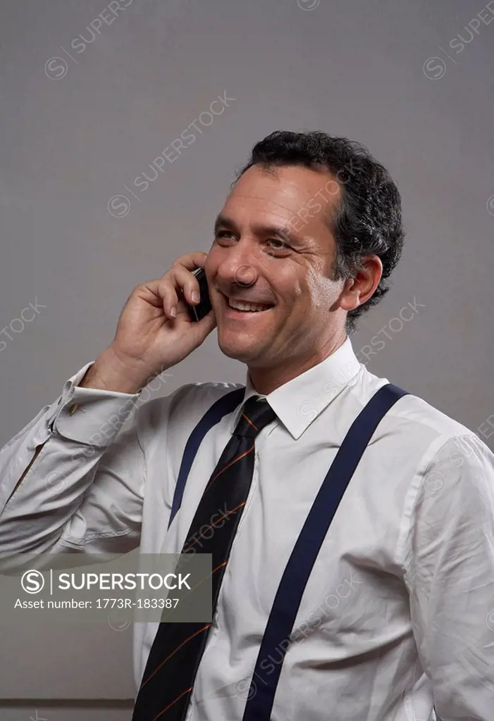 Mature man in shirt and tie using mobile phone, smiling