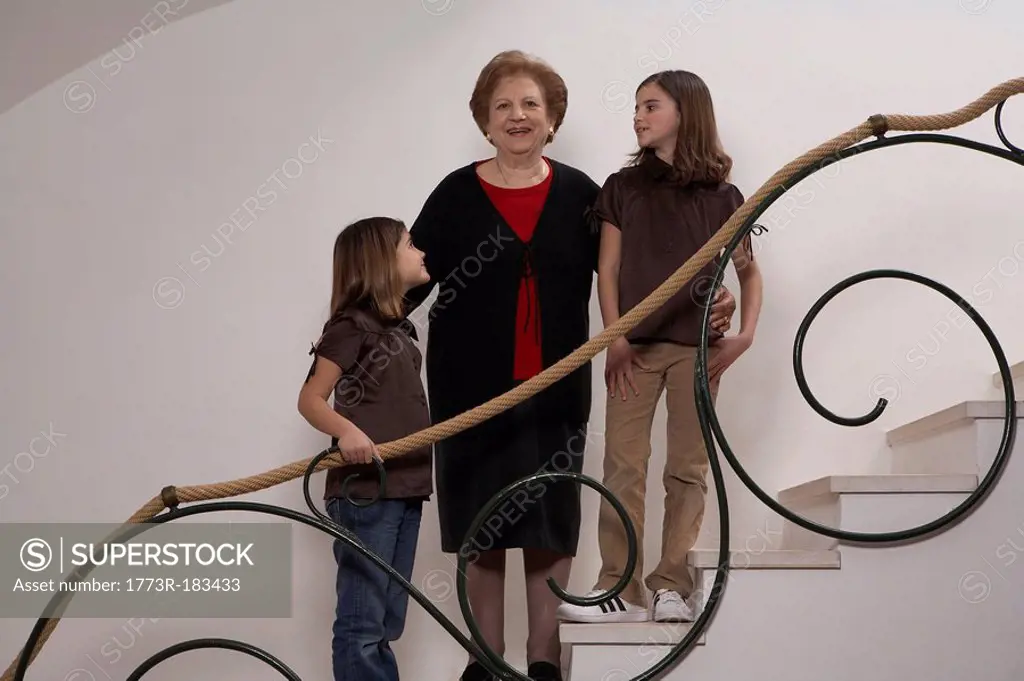 Two granddaughters 6-11 looking at grandmother on staircase