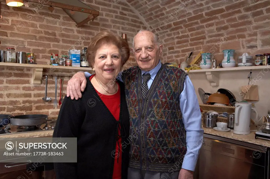 Senior couple in kitchen, smiling, portrait