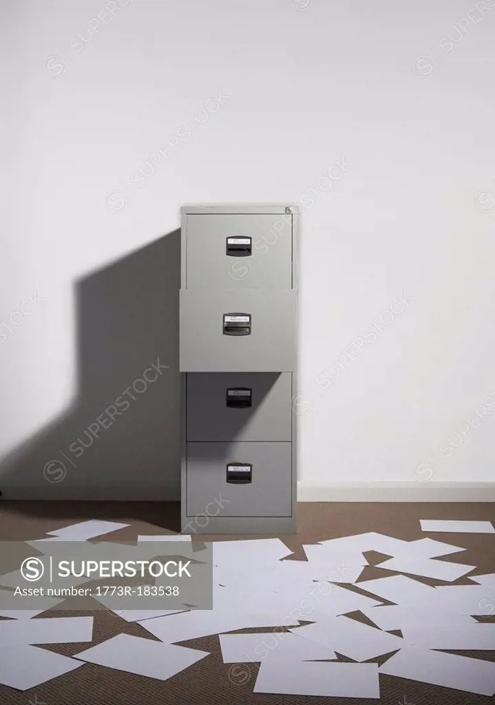 Filing cabinet against wall with papers strewn about
