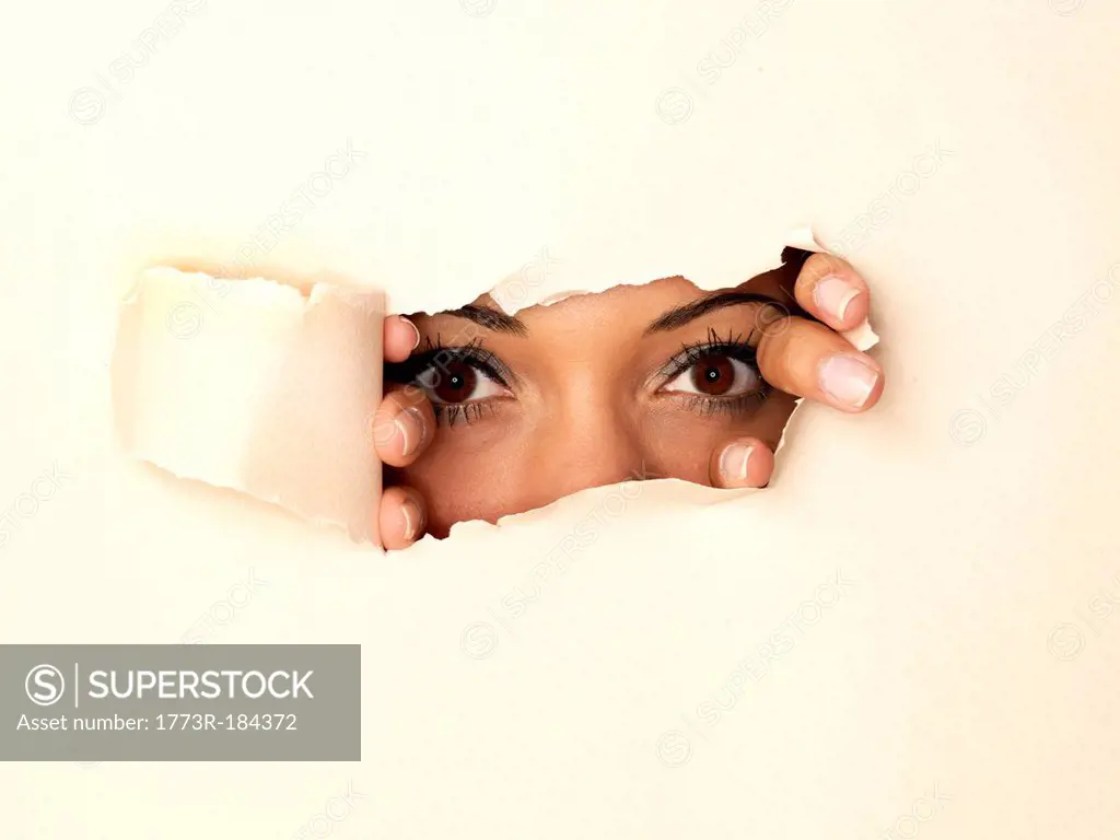 Woman peeking through hole in wall