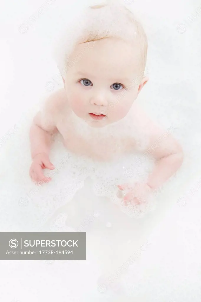 Baby girl sitting in bubble bath