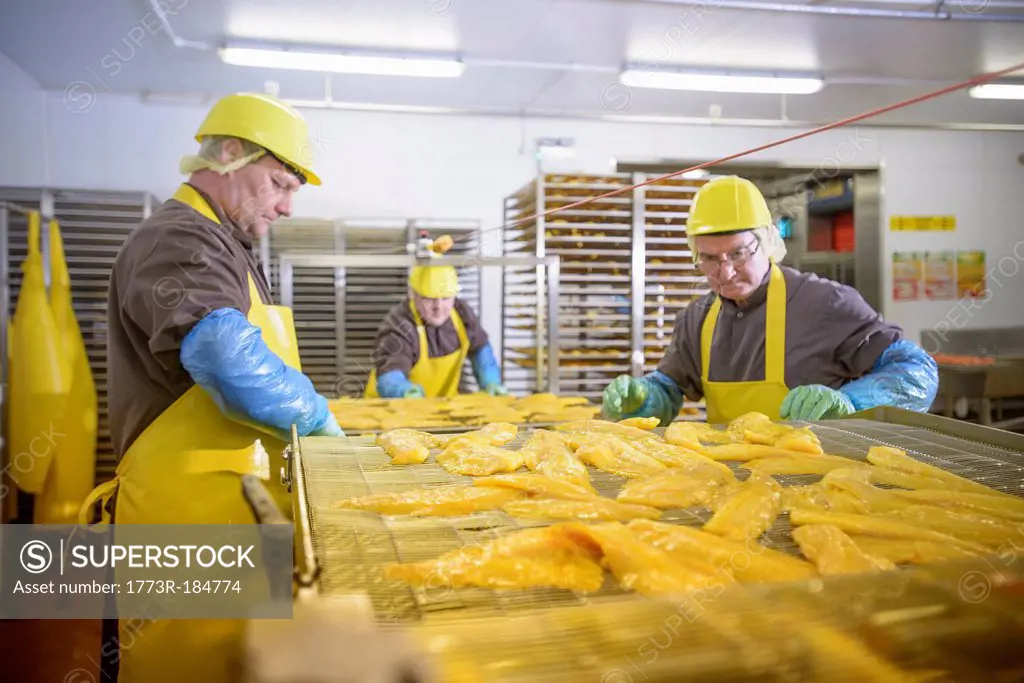 Workers examining smoked fish in factory