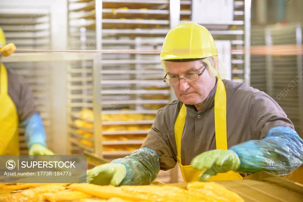 Worker examining smoked fish in factory