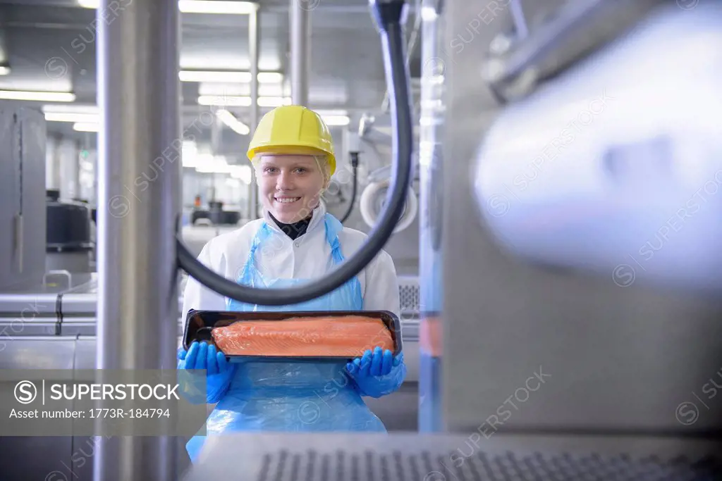 Worker holding fish filet in factory