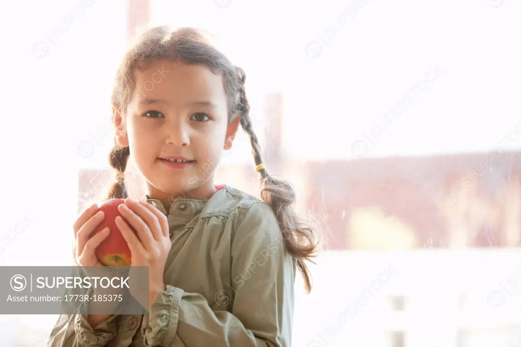 Girl holding apple by window