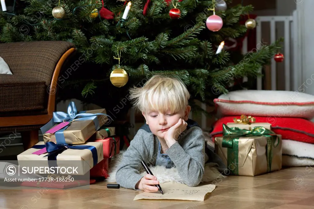 Boy writing under Christmas tree