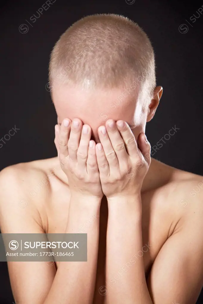 Nude woman covering her face