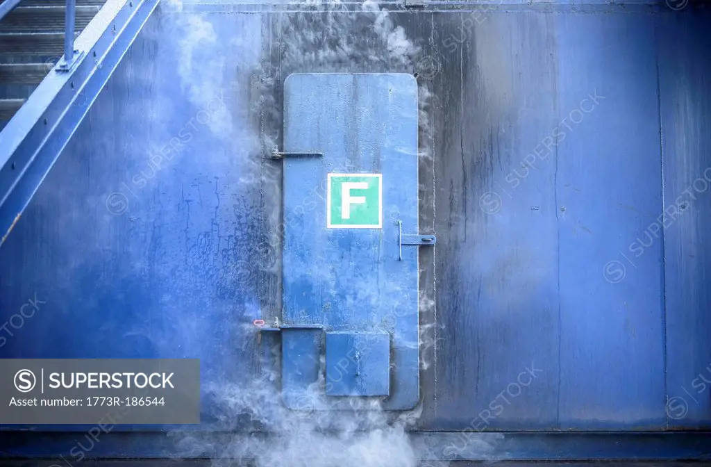 Smoke pouring from behind steel door