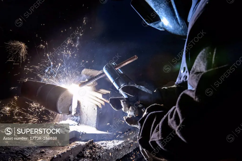 Worker welding metal in foundry
