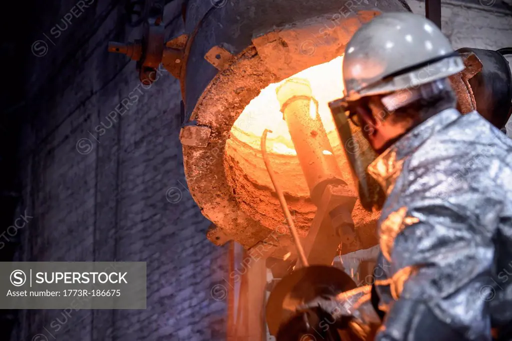 Worker cleaning metal flask in foundry