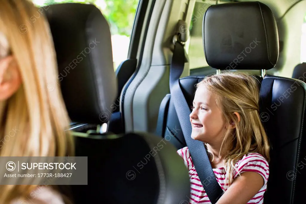 Girl smiling in backseat of car