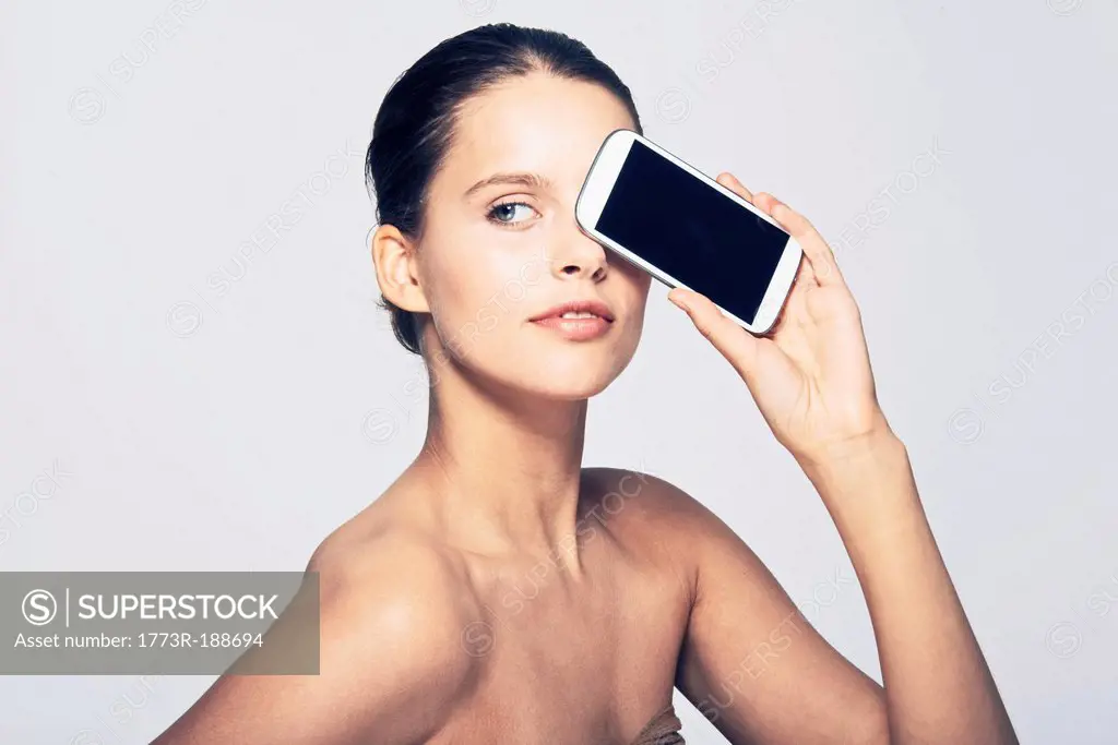 Woman holding cell phone by face
