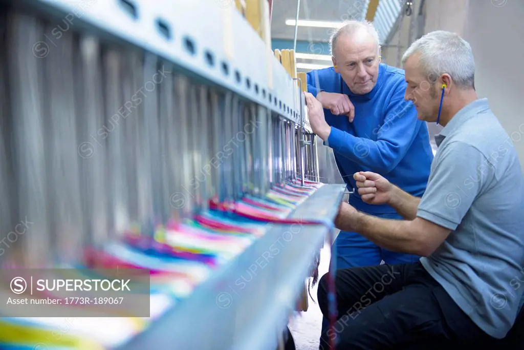 Workers using loom in textile mill
