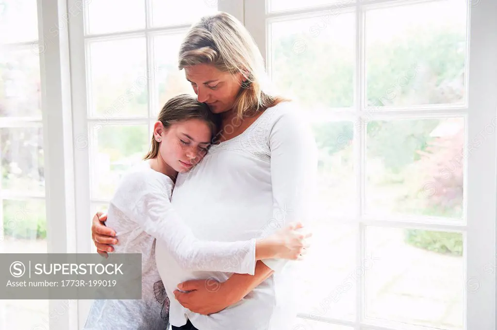Pregnant mother with teenage daughter by window