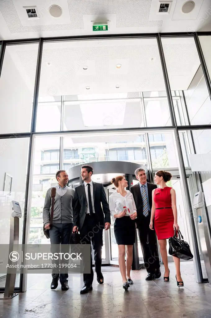 Group of business people talking and entering into glass office building