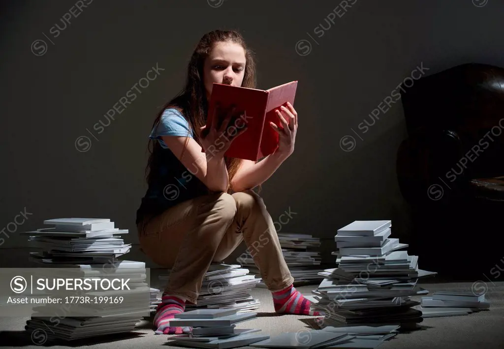 Girl sitting on pile of books reading