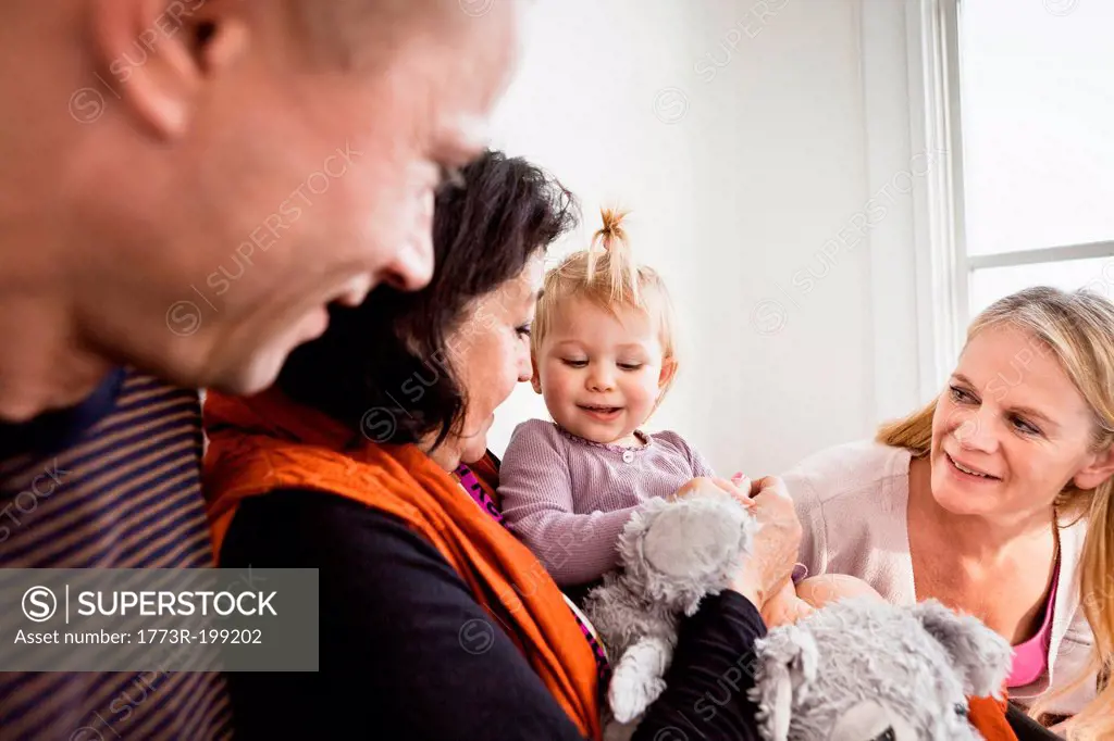 Grandmother holding toddler granddaughter with parents