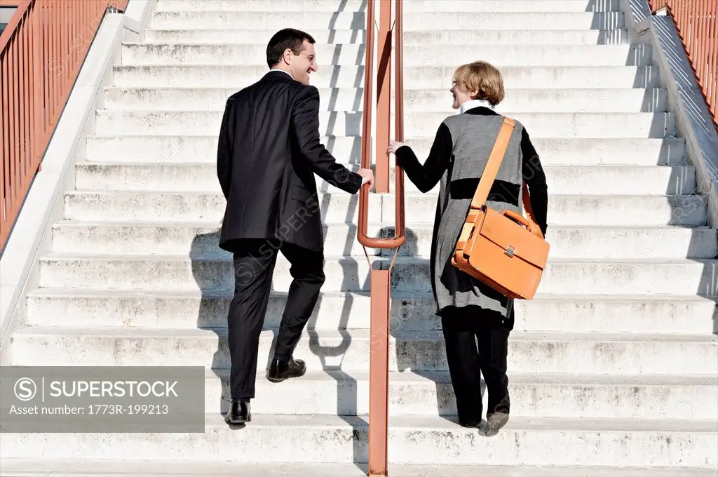 Businesswoman and man ascending staircase, outdoors