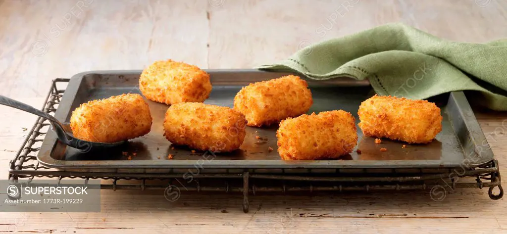 Potato croquettes on baking sheet on wire rack