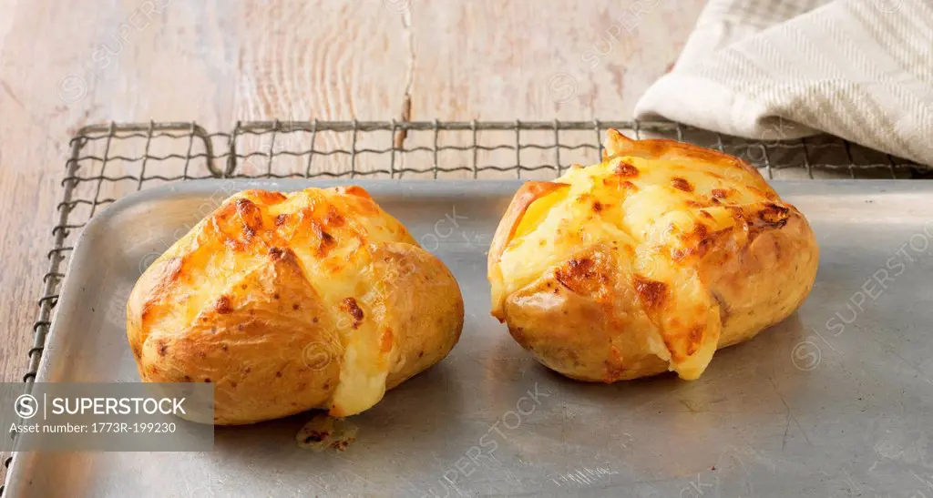 Baked potatoes with cheese on metal baking sheet