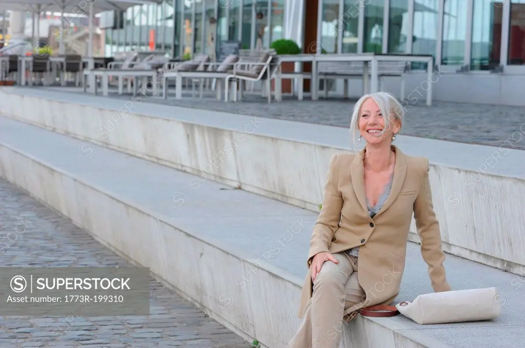 Senior woman sitting on steps in city