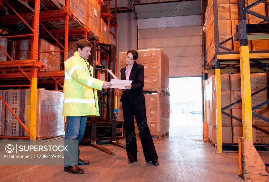 Man and woman looking at paperwork in warehouse