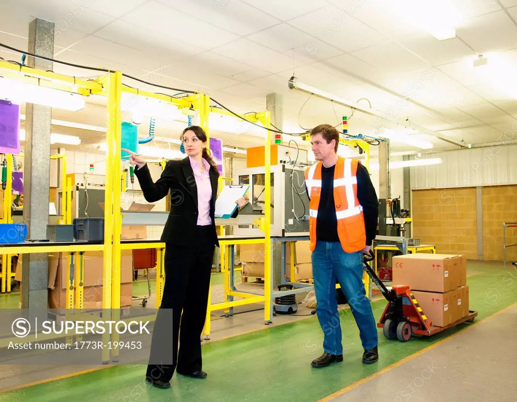 Supervisor directing worker in factory