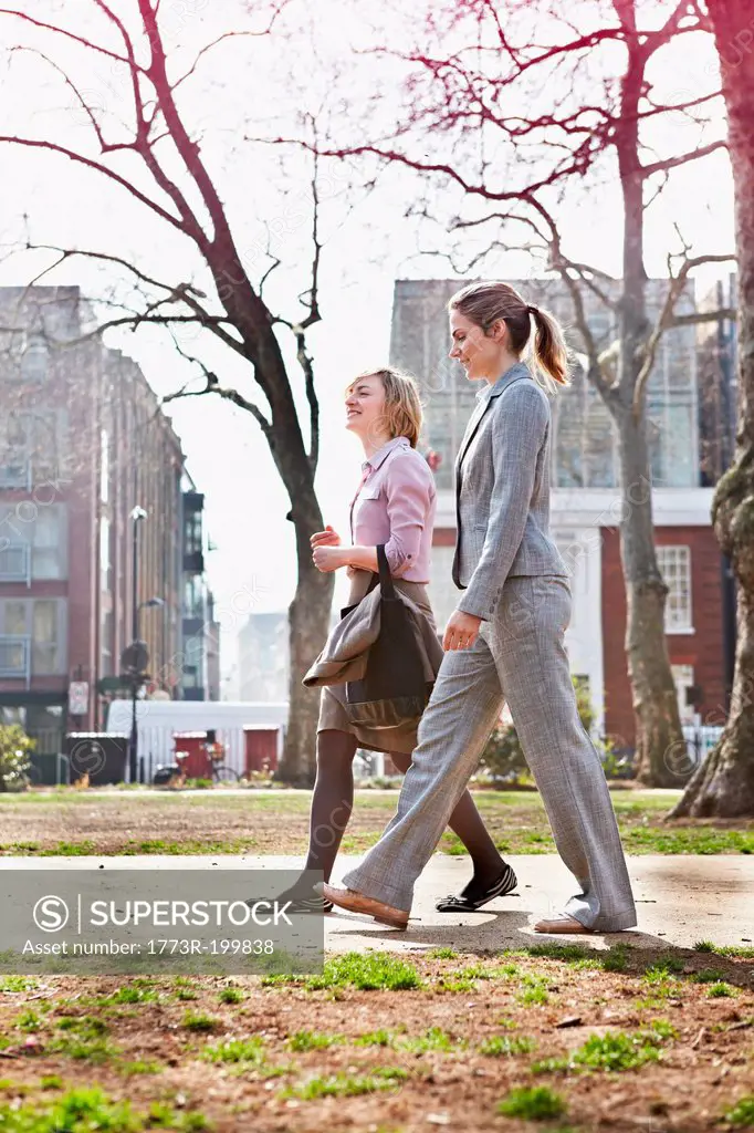 Two businesswomen walking on path in park