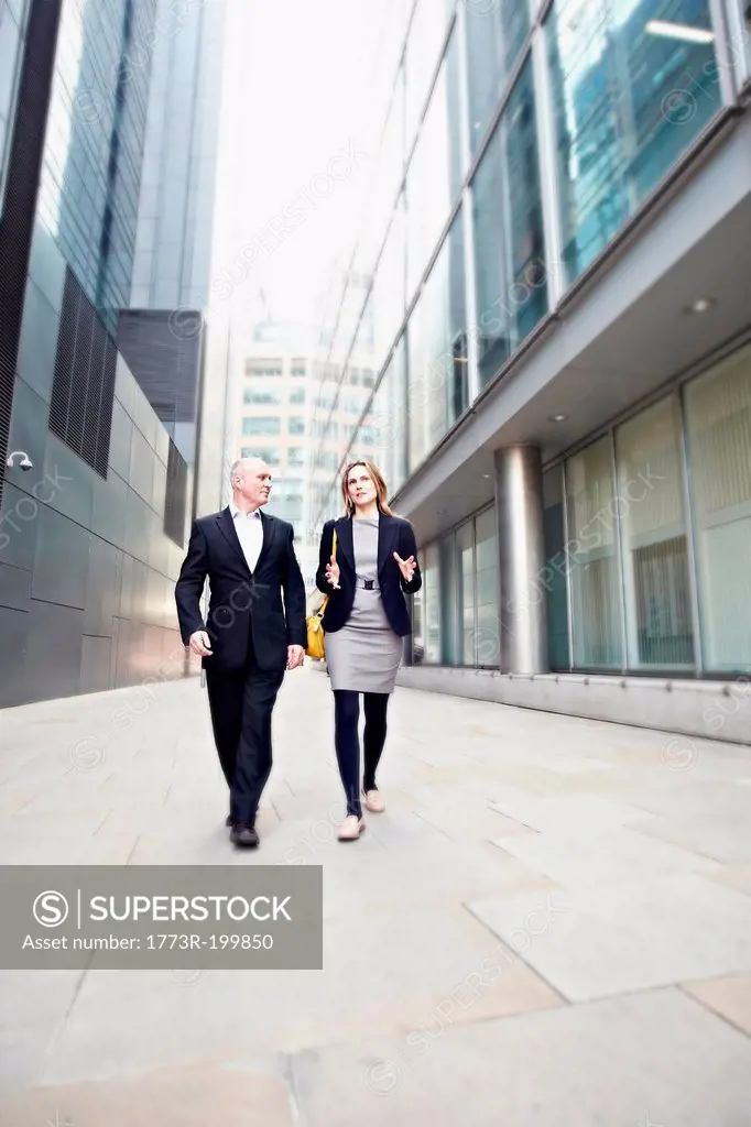 Businessman and businesswoman walking past office buildings