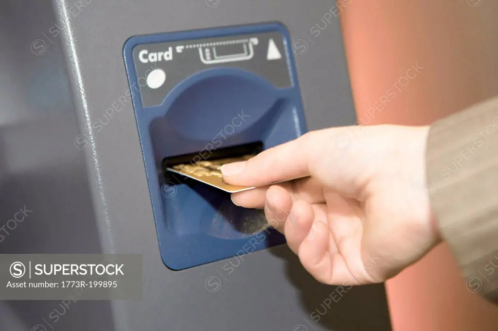 Woman inserting credit card into cashpoint