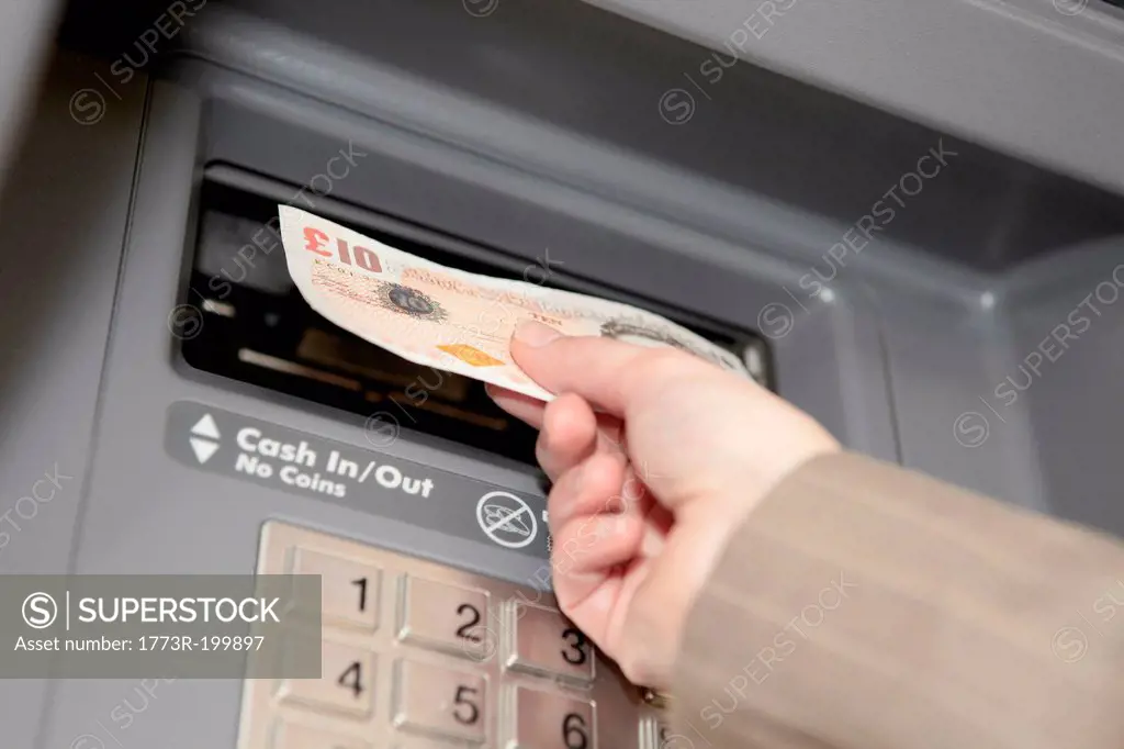 Woman withdrawing ten pound note from cashpoint