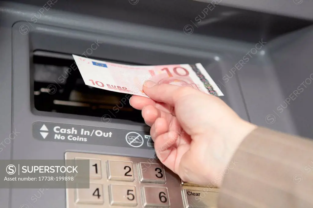 Woman withdrawing ten euro note from cashpoint