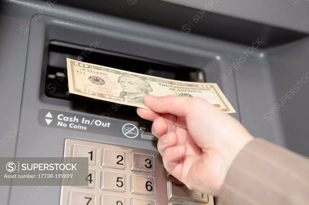 Woman withdrawing ten dollar note from cashpoint