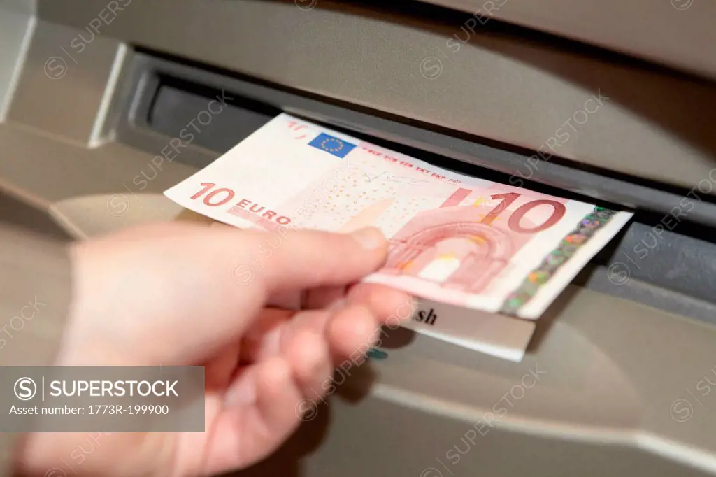 Woman withdrawing ten euro note from cashpoint