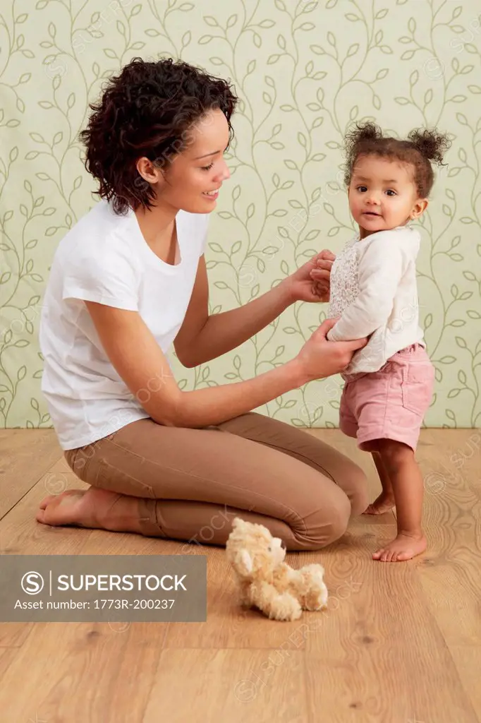 Mother holding baby girl taking first steps