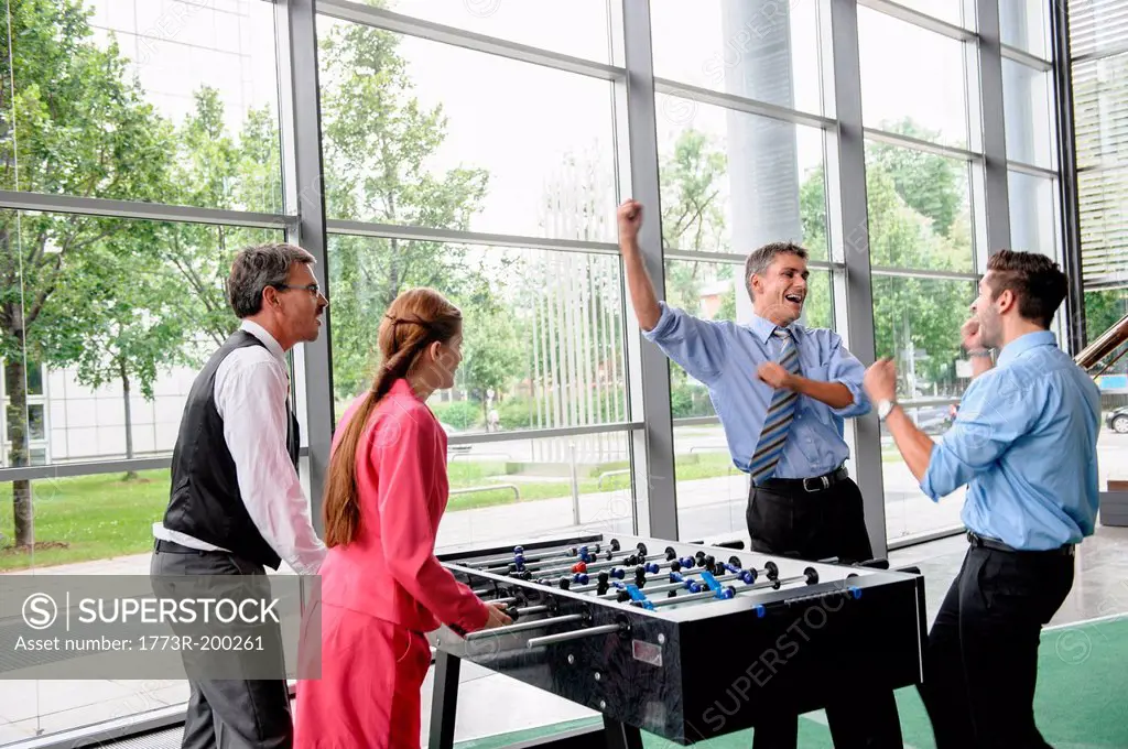 Businessmen winning at table football in lobby
