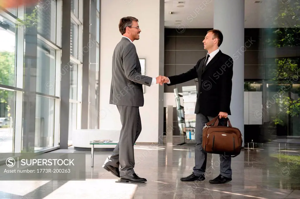 Businessmen shaking hands in lobby