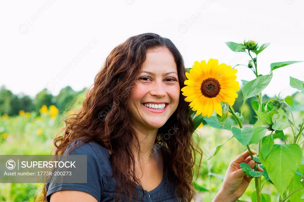 Portrait of young woman with yellow sunflowers in allotment