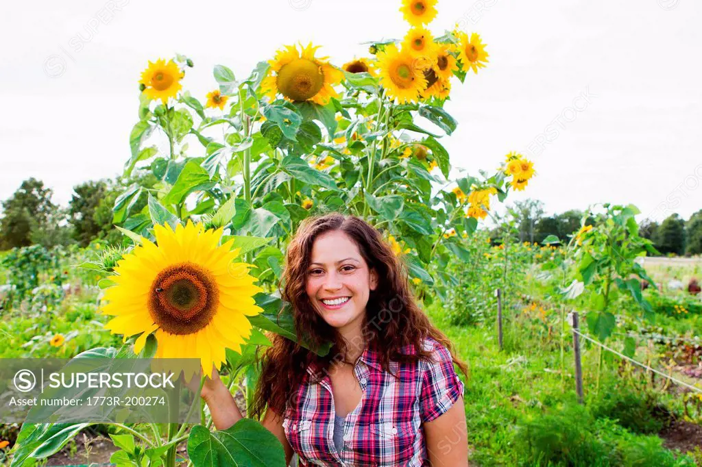 Portrait of young woman with yellow sunflowers in allotment