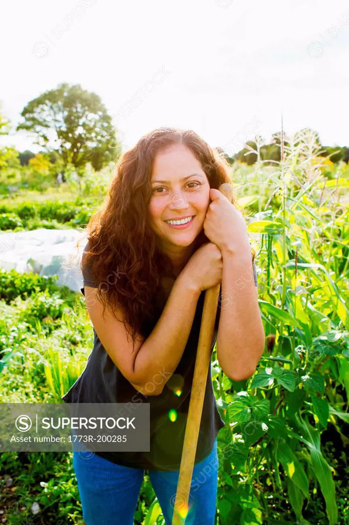 Portrait of young woman leaning on garden tool in allotment