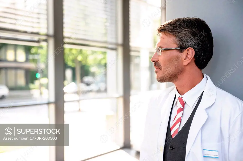 Mature doctor in lab coat looking away